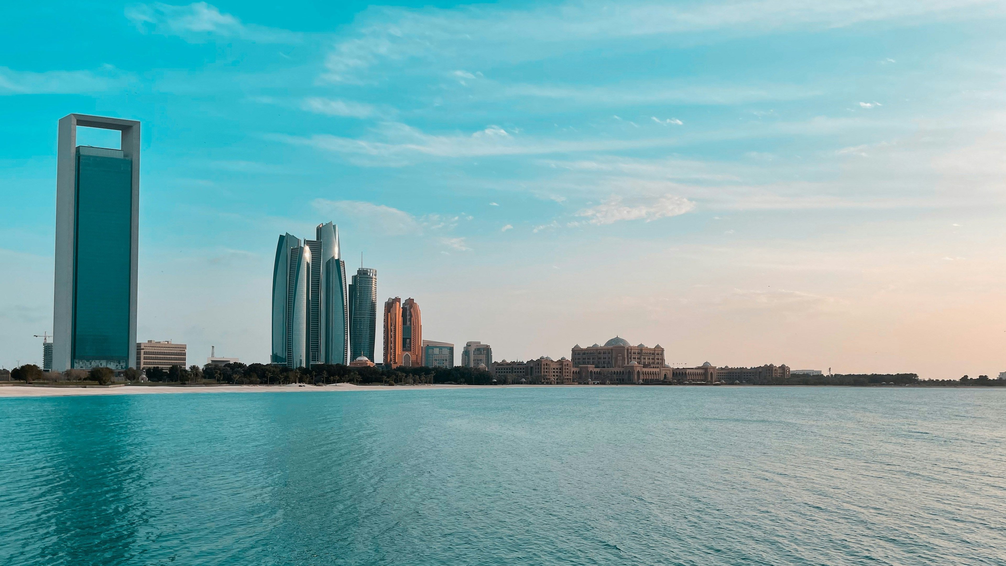 Orizontul orașului Abu Dhabi deasupra apei – zgârie-nori moderni pe un cer albastru.