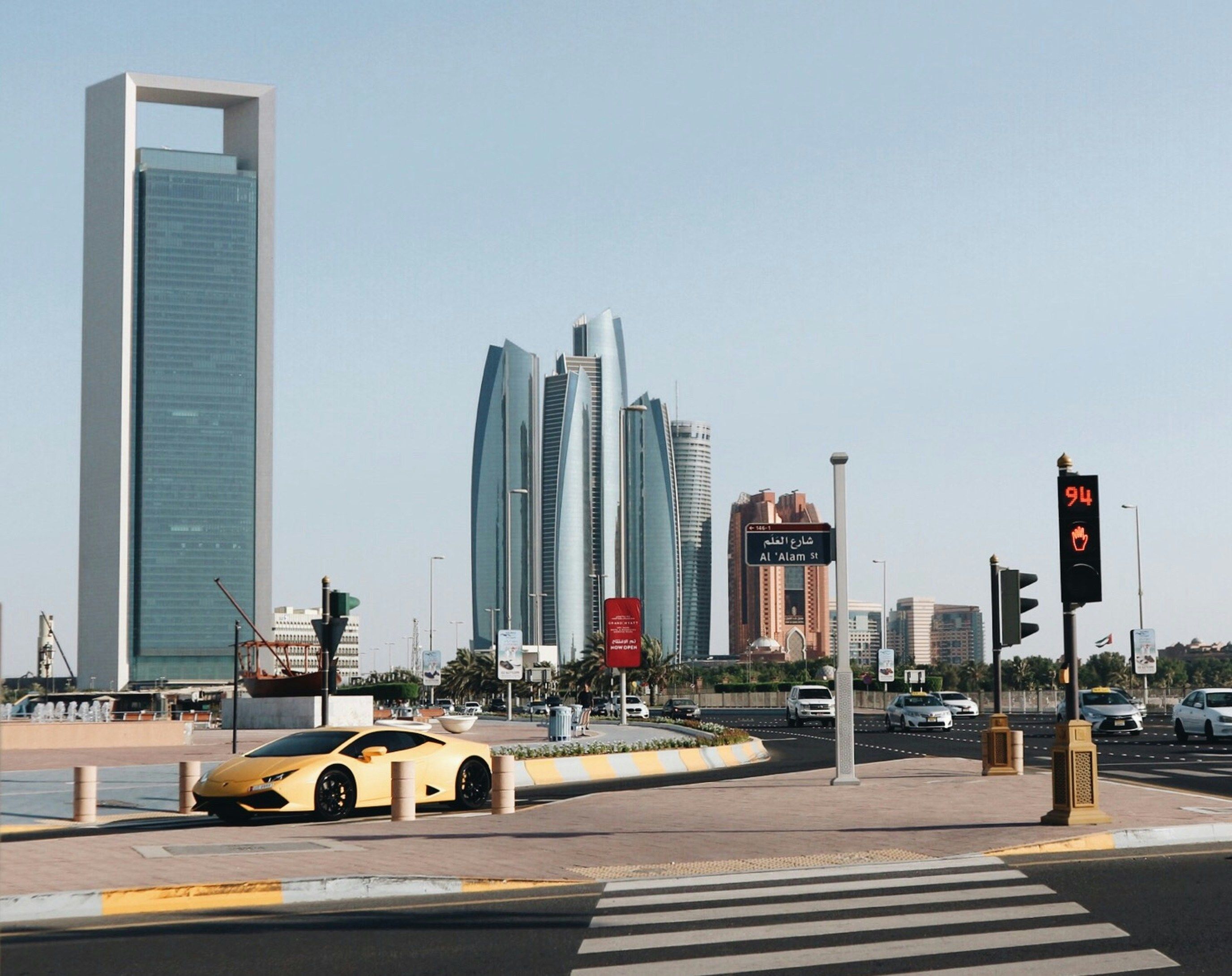 bu Dhabi city skyline by a wide road, with a yellow sports car in the foreground.